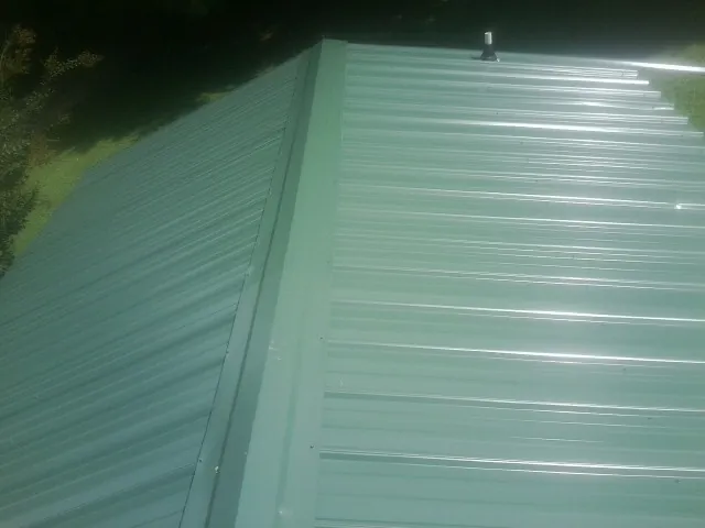 New green metal panels meeting at the ridge of a roof — Flat Roof Repair work by our crew in Winburne