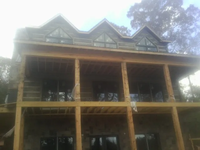 Dormers and porch framing on a large log home under construction — Roof Coating work by our crew in Winburne