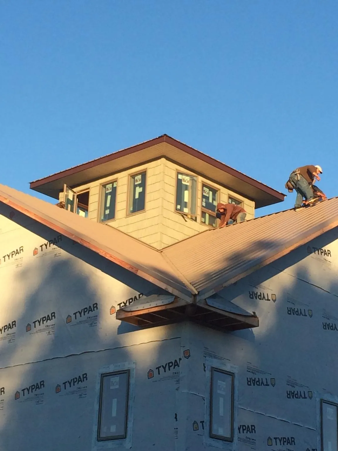 Roofers working around a rooftop cupola on a new metal roof at sunset — Roof Waterproofing in Winburne by Roofing Brothers